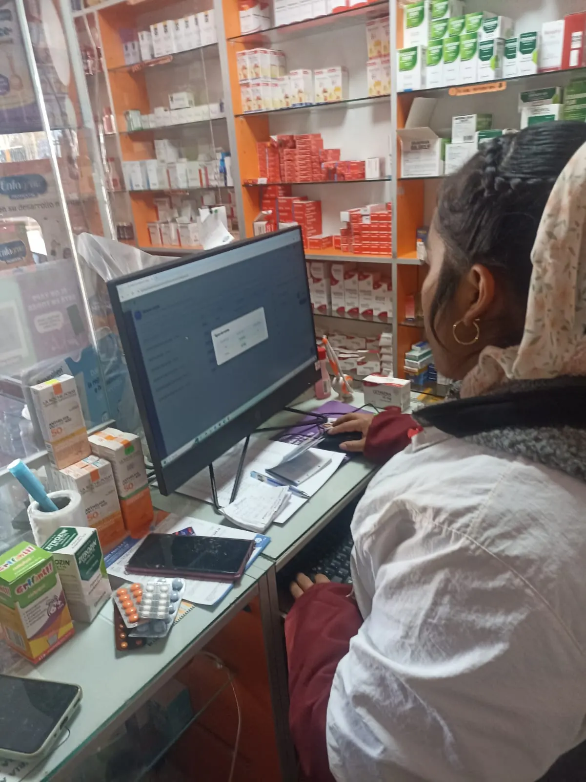 Regente de botica atendiendo con el sistema MEDEX en pantalla